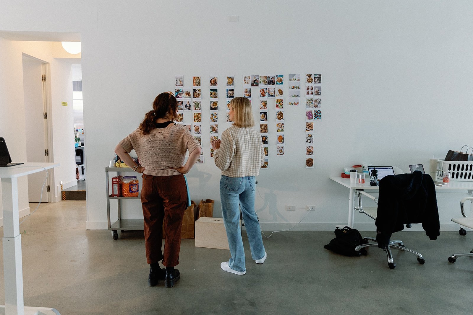 Monique Volz of Ambitious Kitchen standing in front of a wall of recipe photos with a designer