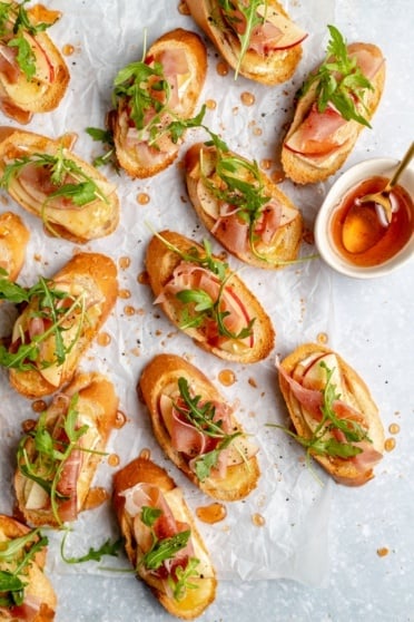 apple and brie crostini with hot honey on parchment paper