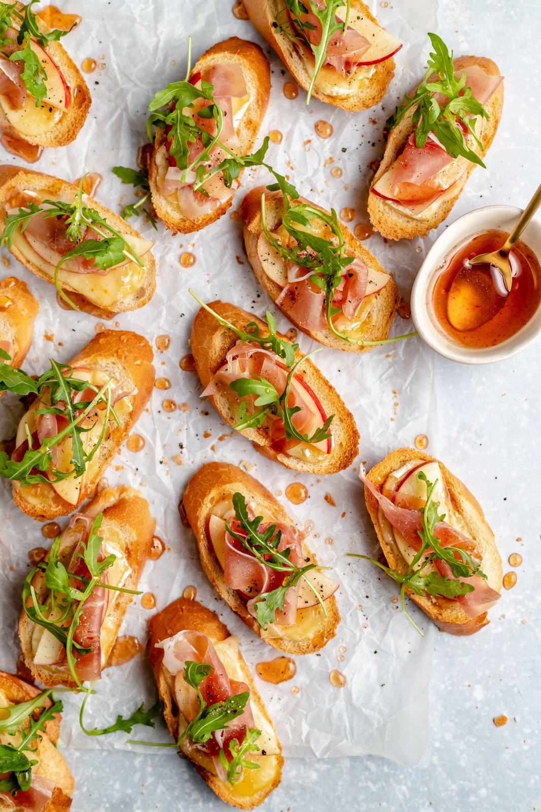 apple & brie crostini with hot honey on parchment paper