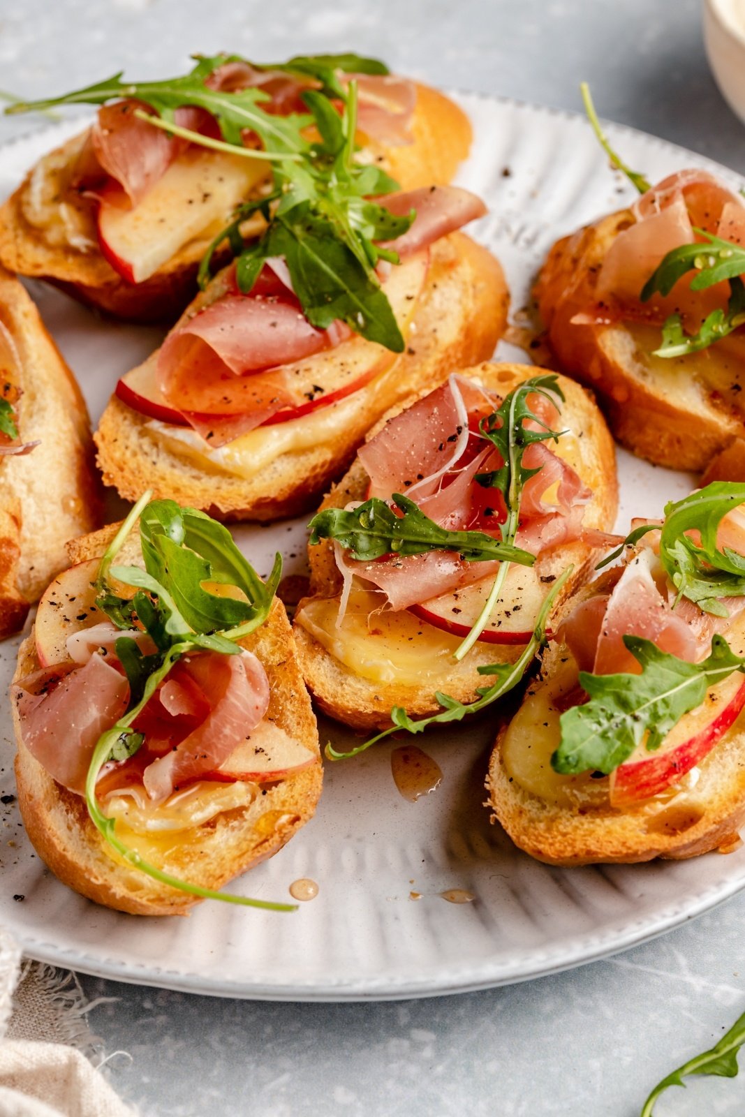 simple apple and brie crostini with prosciutto on a plate