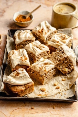 apple cake with brown butter frosting sliced on a baking pan