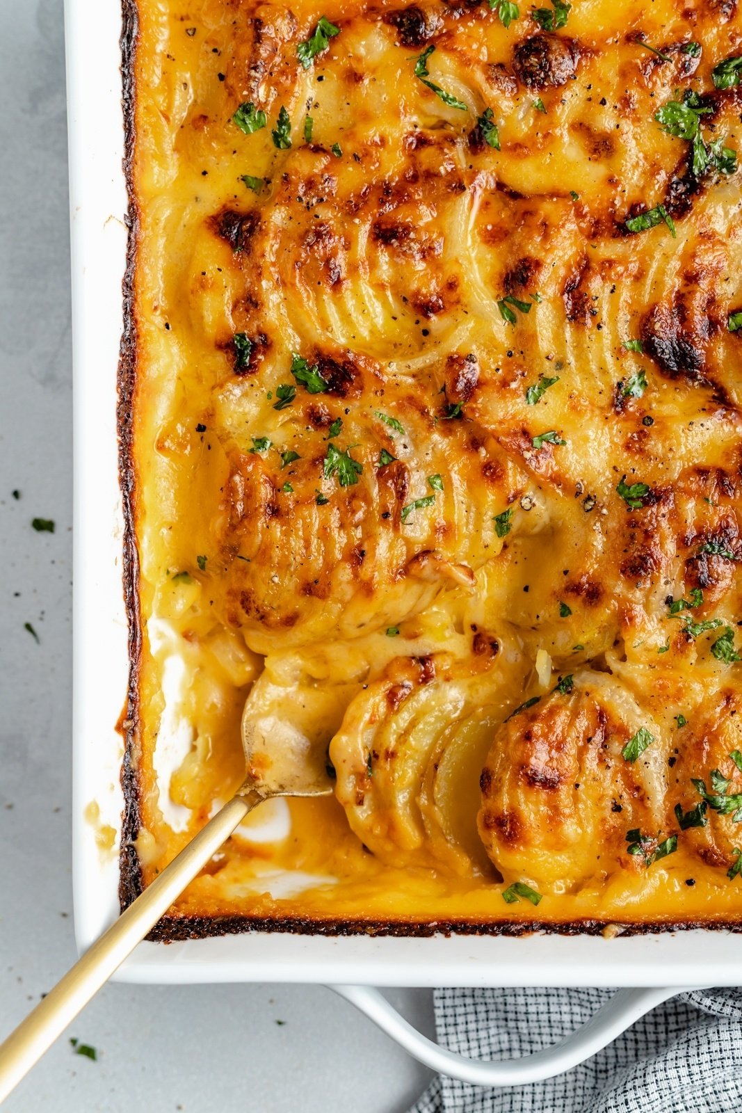 cheesy au gratin potatoes in a baking dish with a spoon