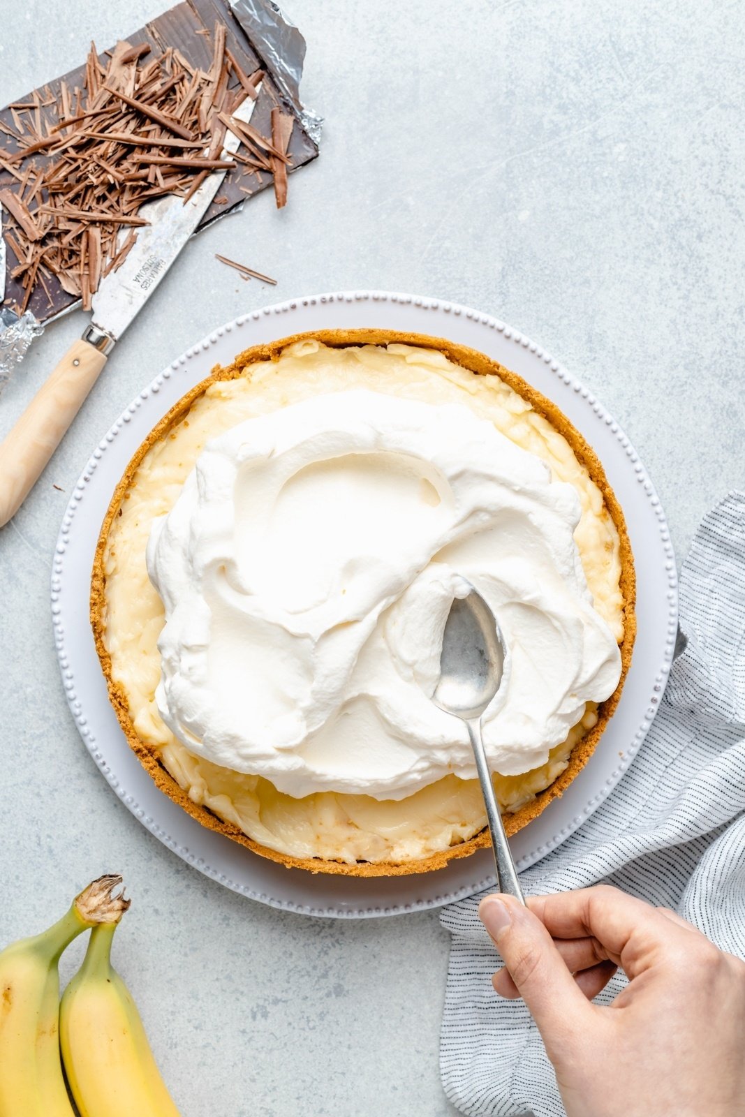 topping an easy banana cream pie with whipped cream