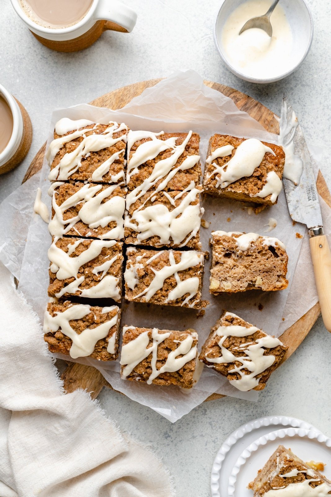 sliced apple coffee cake with glaze on parchment paper