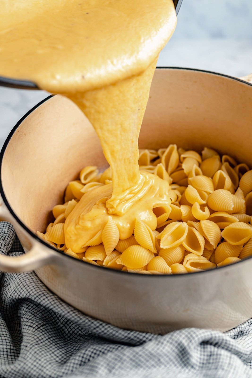 pouring cheese sauce onto buffalo mac and cheese