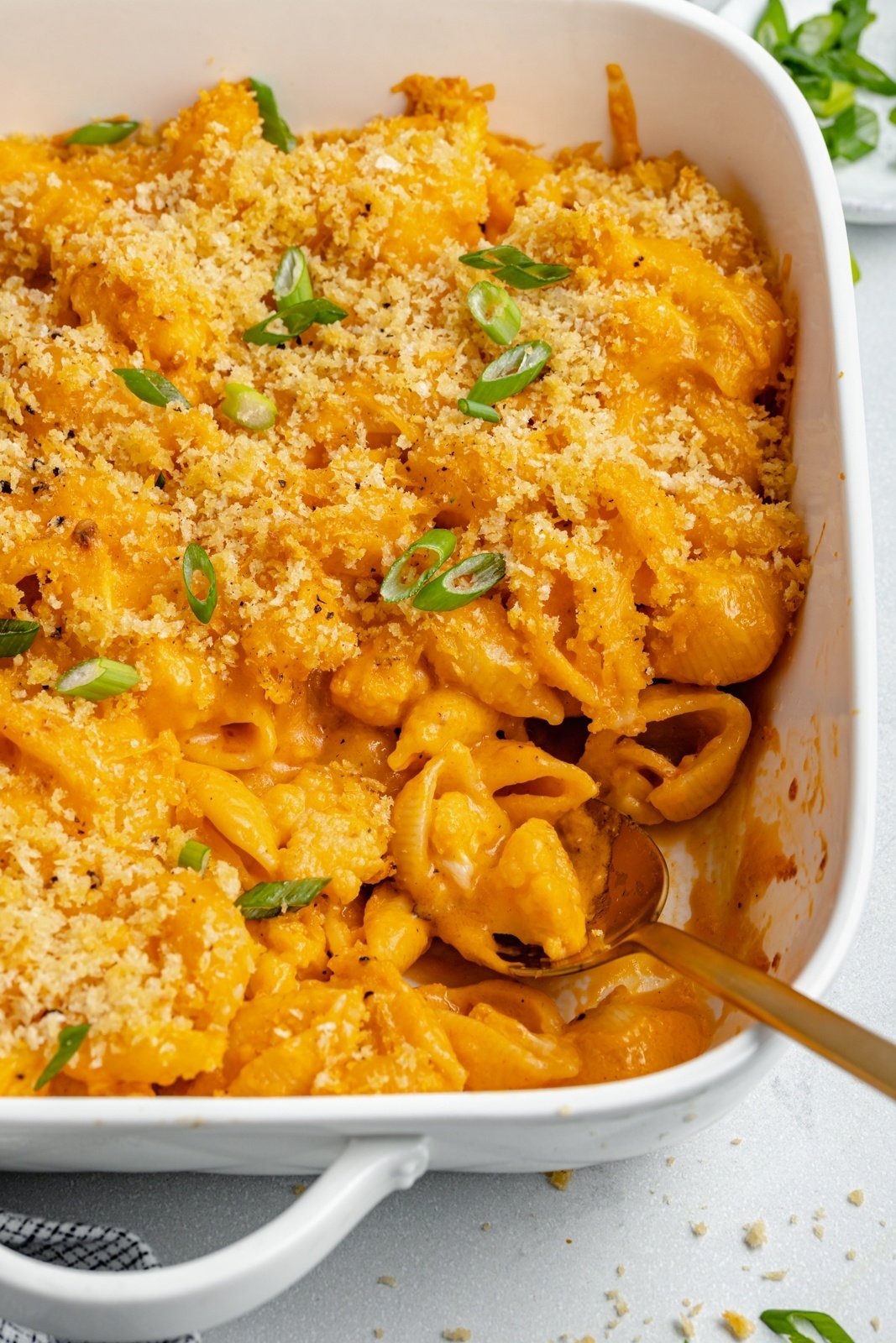 scooping buffalo cauliflower mac and cheese out of a baking dish