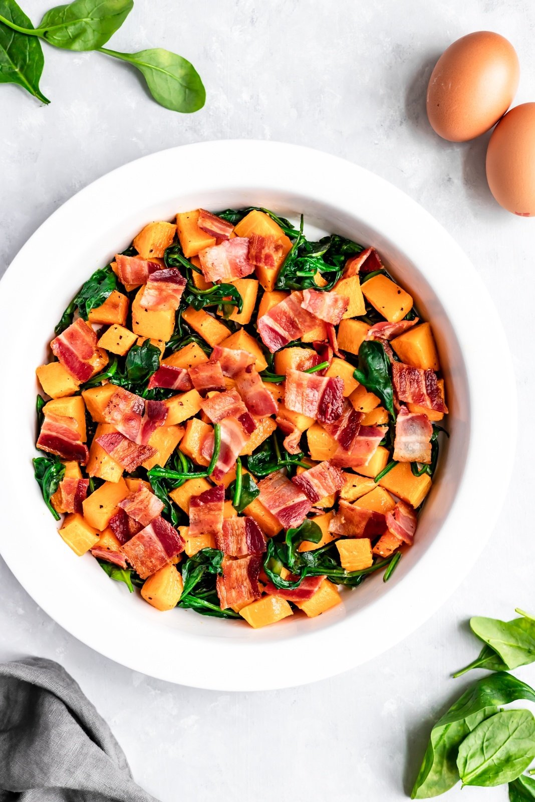 butternut squash quiche ingredients in a pie pan before eggs are poured in