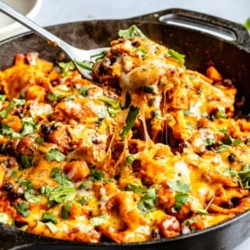 scooping up an enchilada skillet from a pan