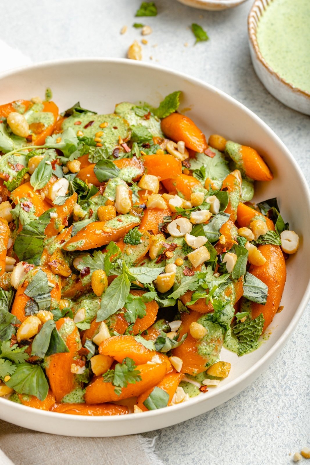 easy caramelized garlic carrots in a bowl with fresh herbs and green sauce