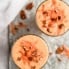 carrot cake smoothie in two glasses topped with pecans and shredded carrot