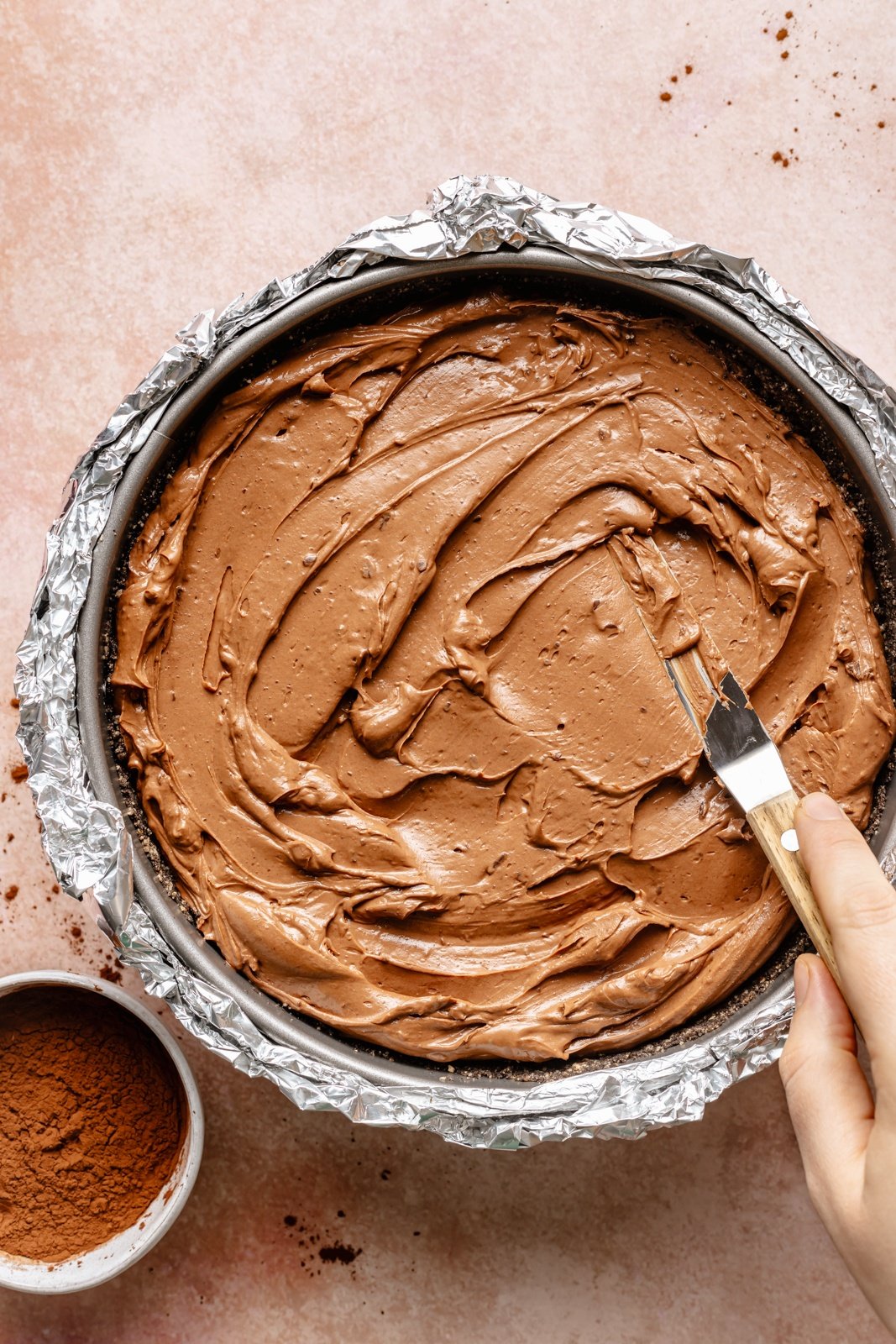 smoothing chocolate cheesecake filling into a pan