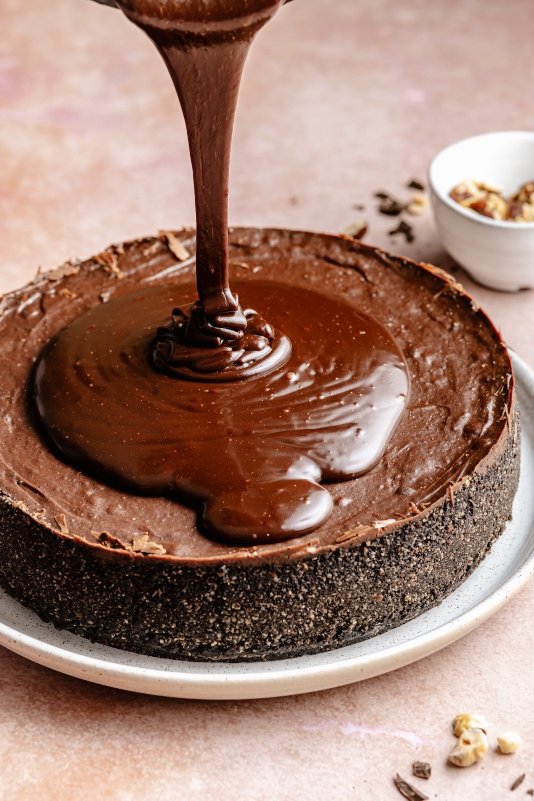 pouring Nutella ganache onto a dark chocolate cheesecake