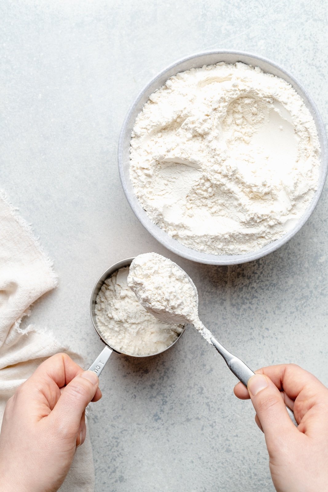 scooping flour into a measuring cup with a spoon