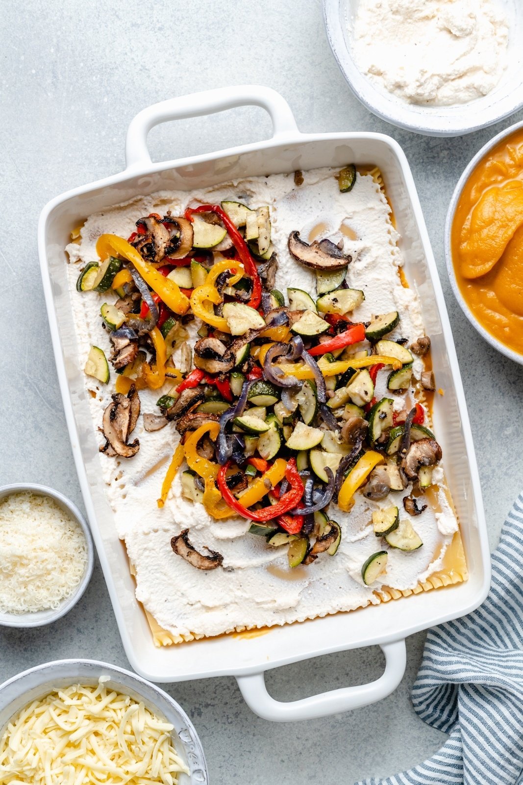 layering a roasted vegetable lasagna in a pan