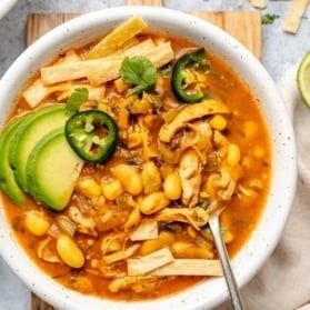 healthy chicken enchilada soup in a bowl topped with garnishes