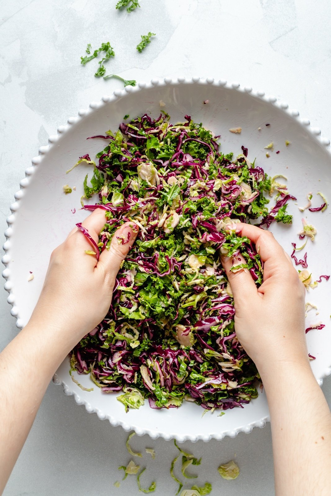 massaging dressing into a brussels sprouts kale apple salad