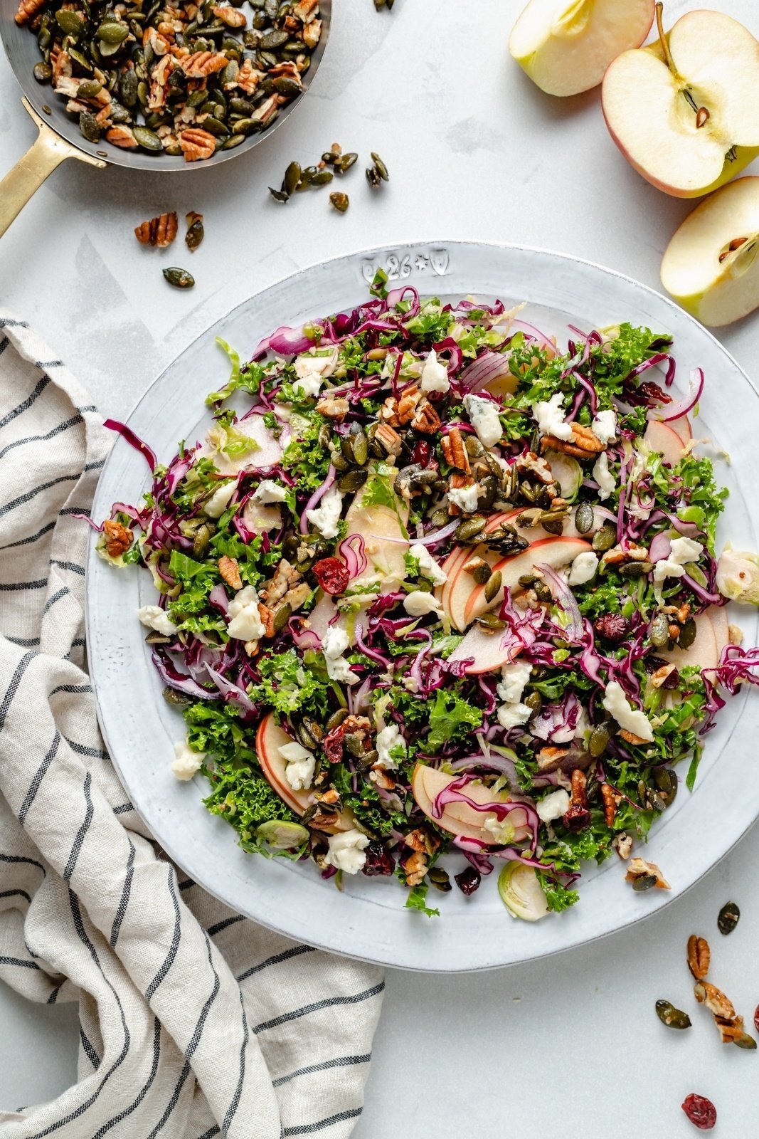 brussels sprouts kale apple salad on a plate with nuts and gorgonzola