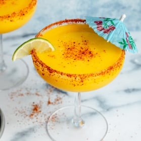 frozen mango margarita in a glass with a blue umbrella