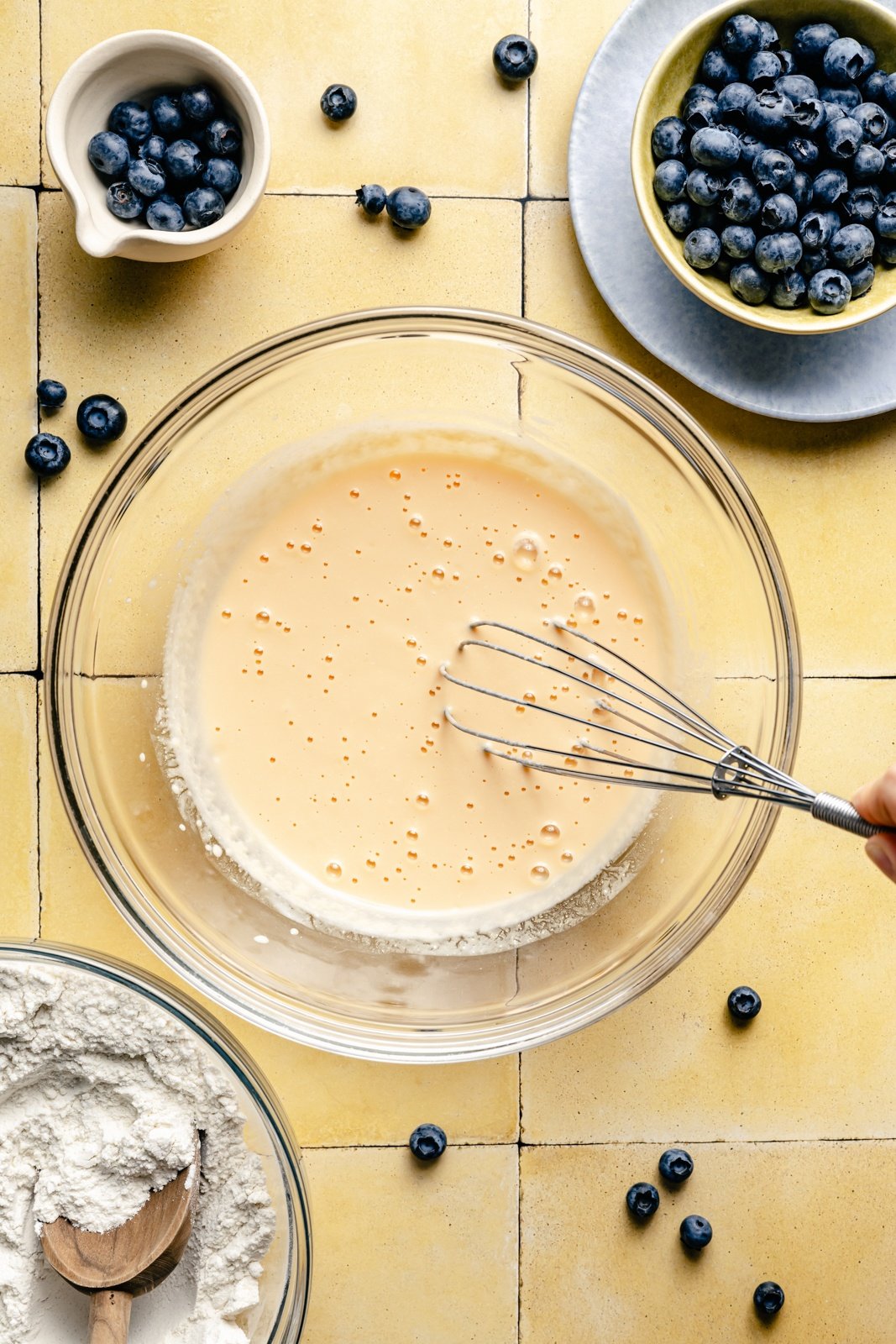 whisking batter for blueberry buttermilk pancakes in a glass bowl