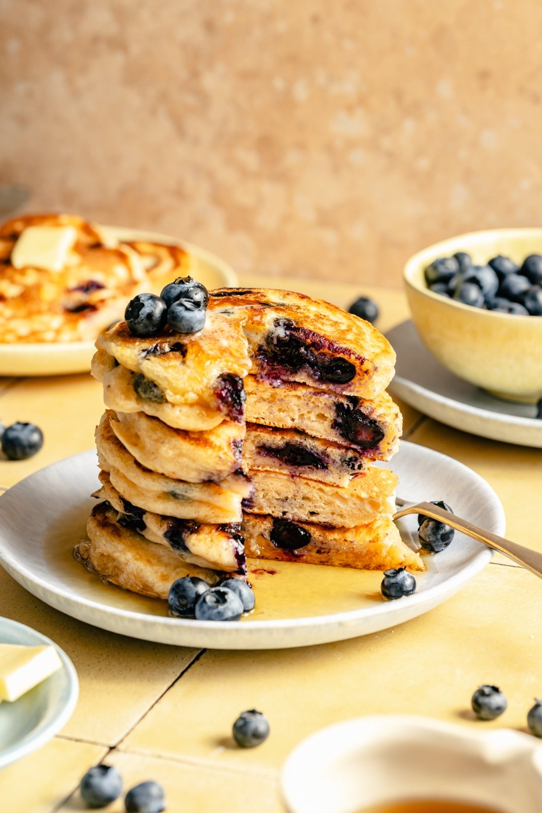 buttermilk blueberry pancakes in a stack on a plate with a slice cut out