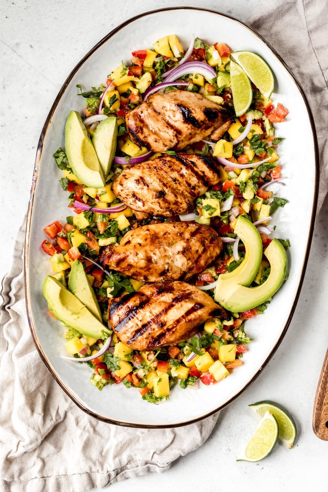 grilled chicken breasts on a platter with veggies