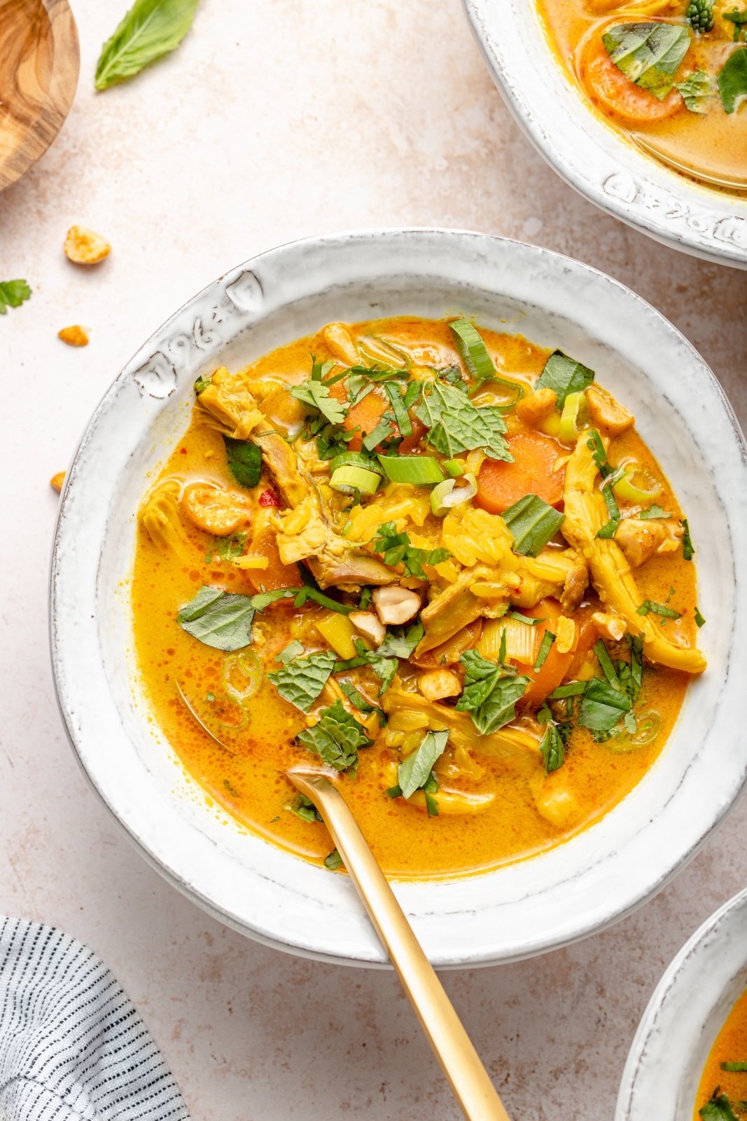 ginger chicken soup in a bowl topped with fresh herbs