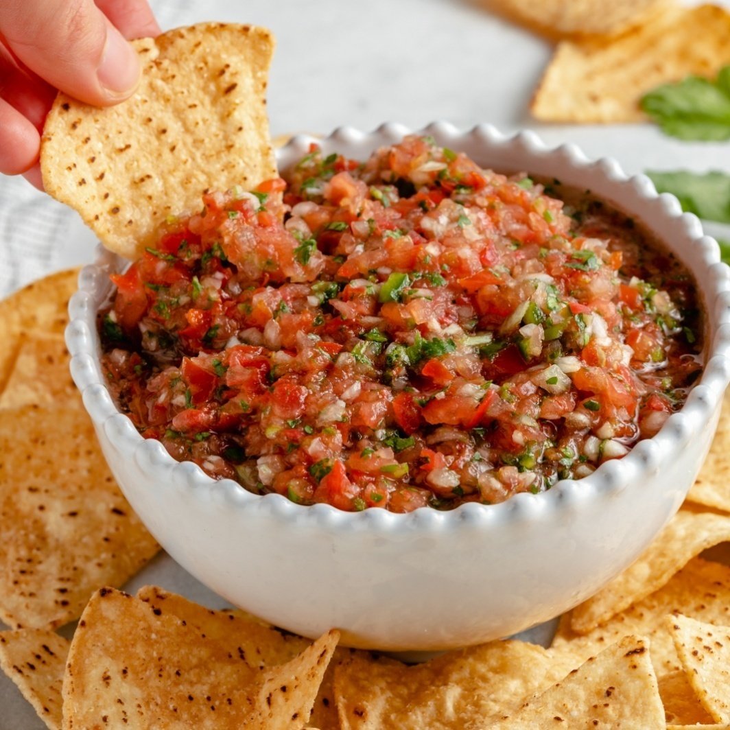 dipping a chip into homemade salsa in a bowl