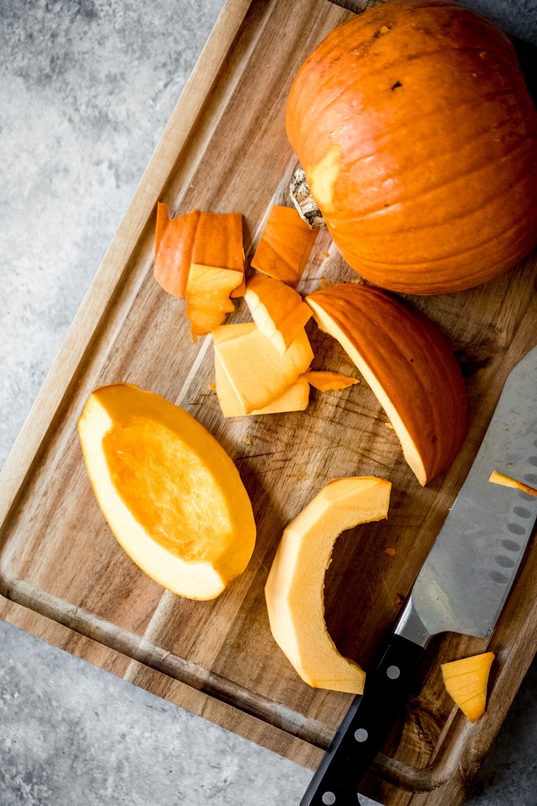 pumpkin cut into pieces on a cutting board with a knife