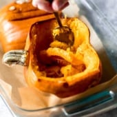 half of a pumpkin in a baking dish with a spoon