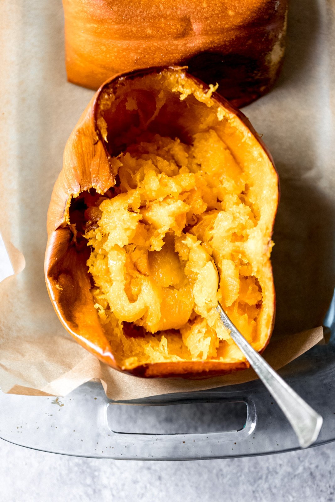 half of a pumpkin in a glass baking dish with the insides mashed