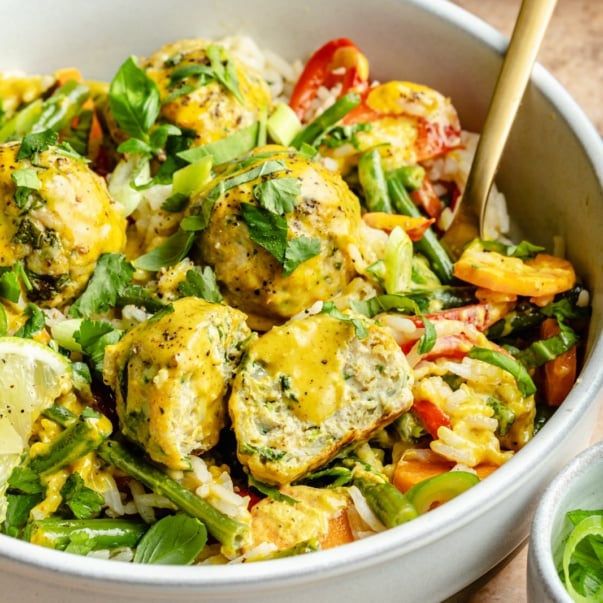 yellow curry chicken meatballs in a bowl with coconut rice and vegetables