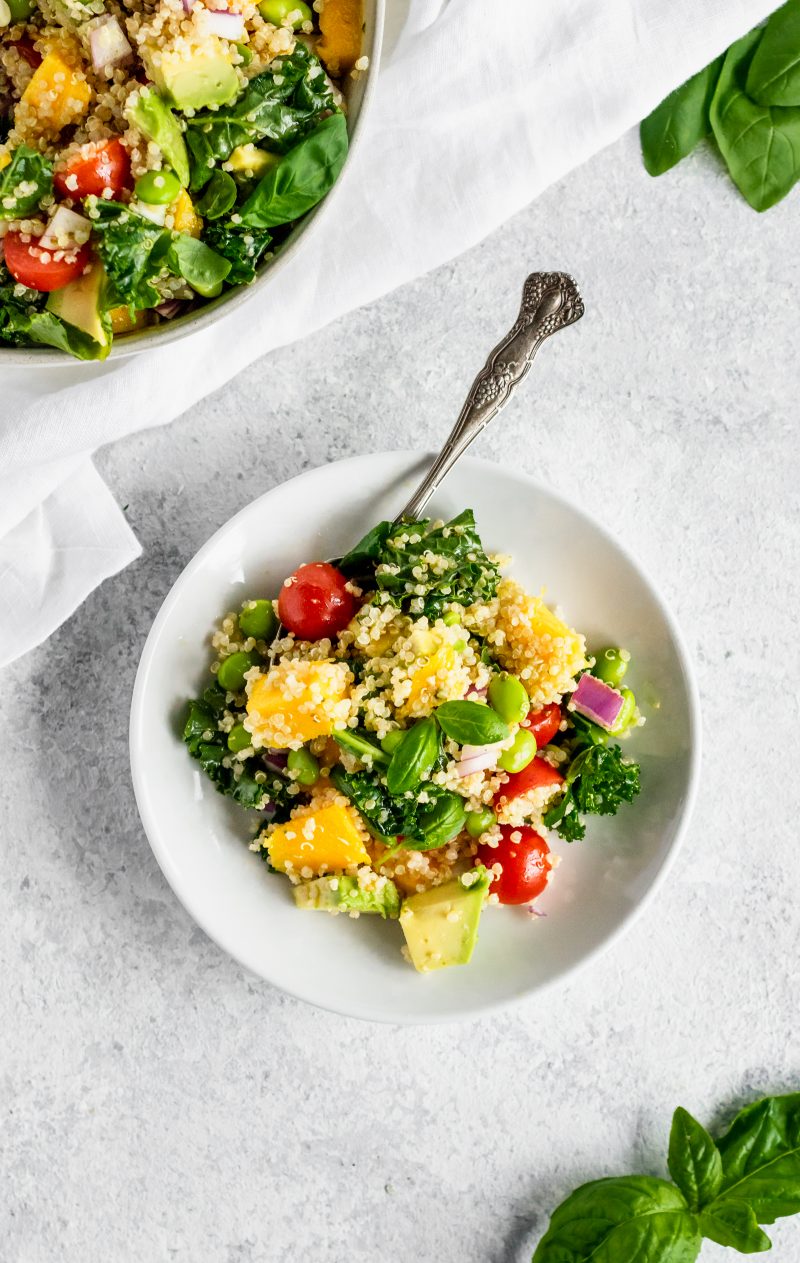 Kale quinoa salad with in a bowl with mango and edamame