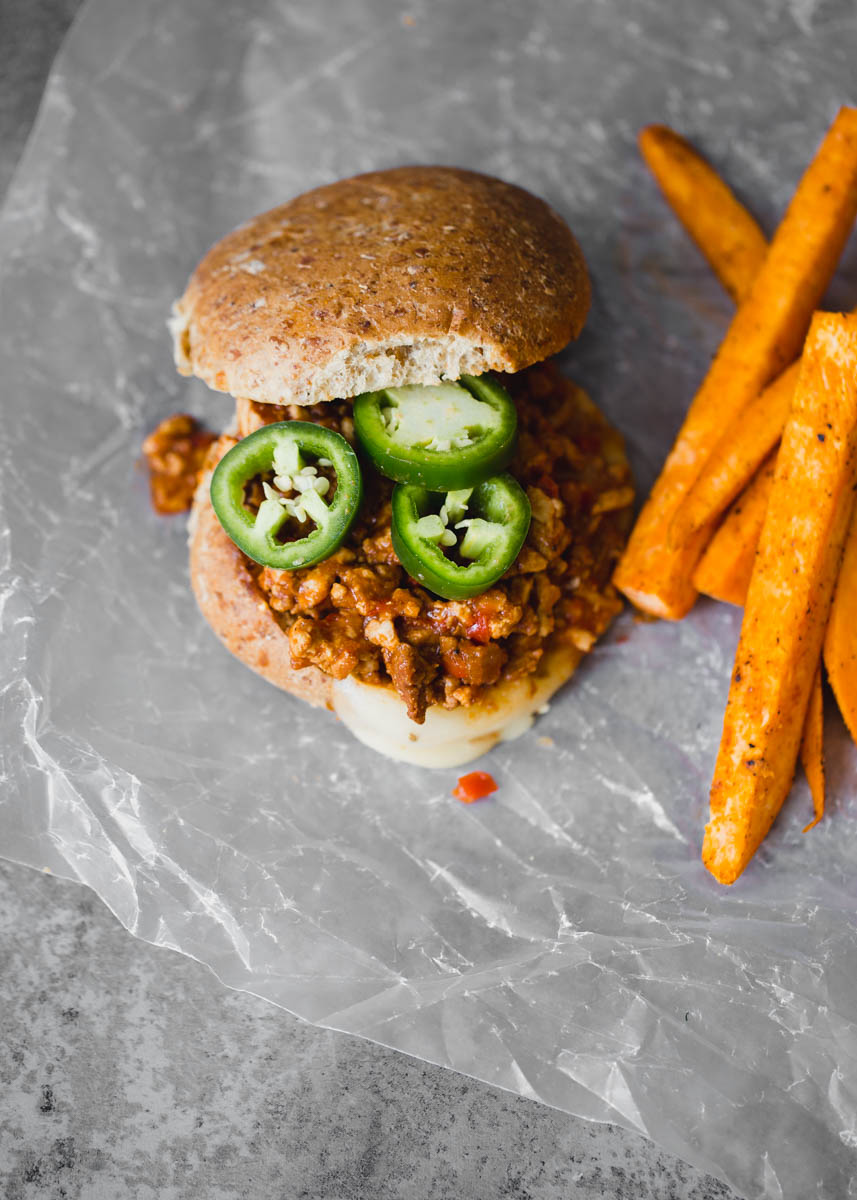 Healthy turkey sloppy joes topped with jalapeño slices next to sweet potato fries