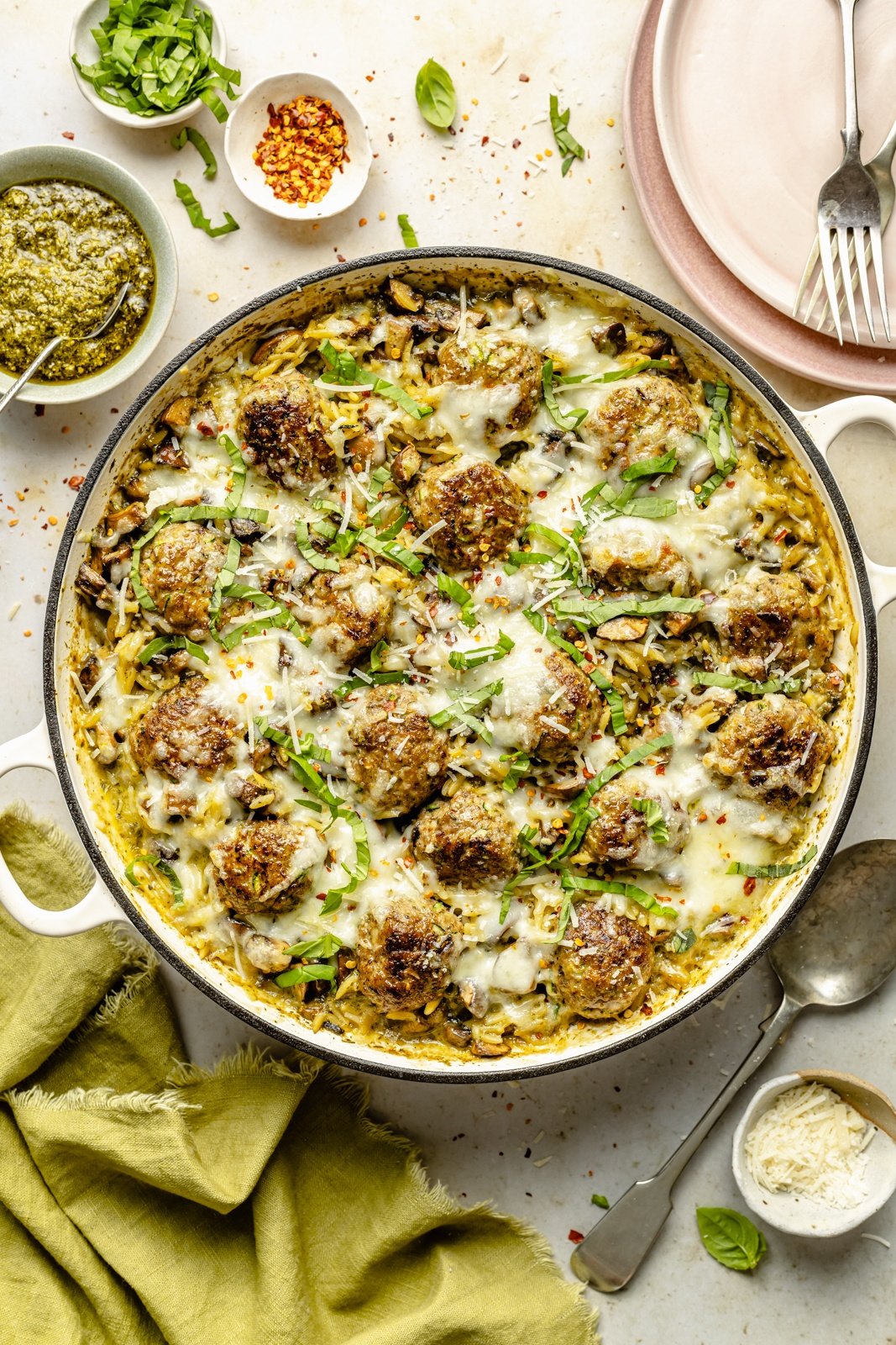 one pan baked pesto orzo with chicken meatballs in a skillet