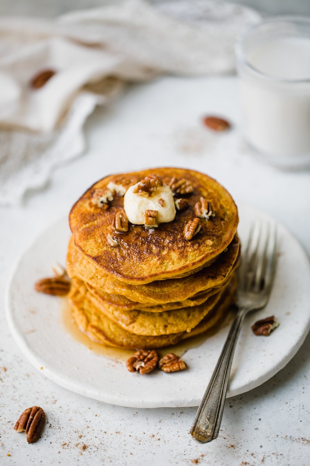 healthy pumpkin pancakes stacked on a plate with a fork on the side