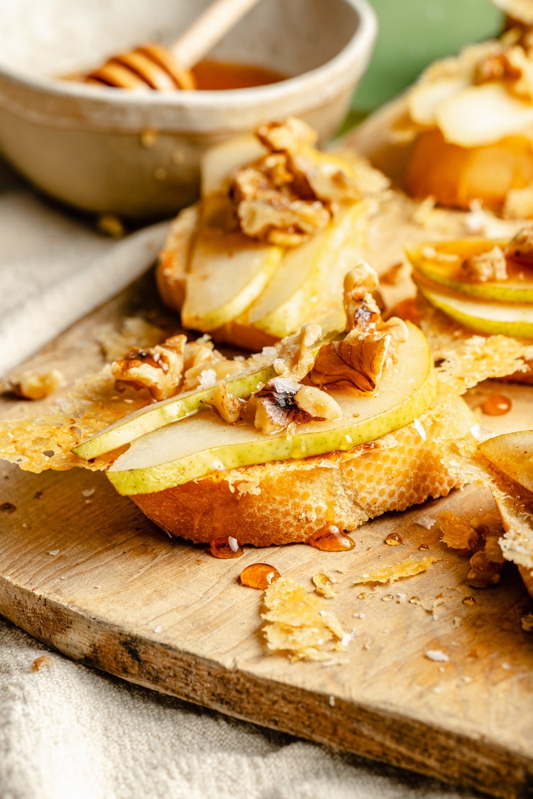 parmesan pear crostini with walnuts and honey on a wooden board