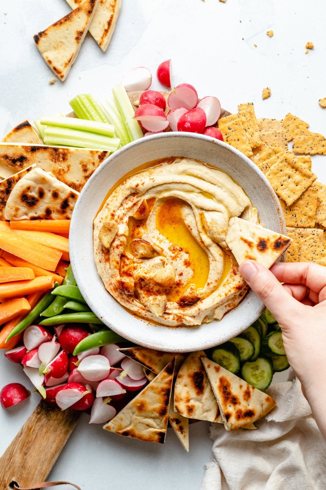 dipping pita into a bowl of roasted garlic hummus