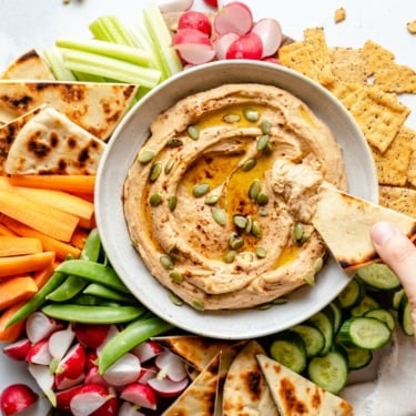 dipping pita bread into a bowl of sweet potato hummus