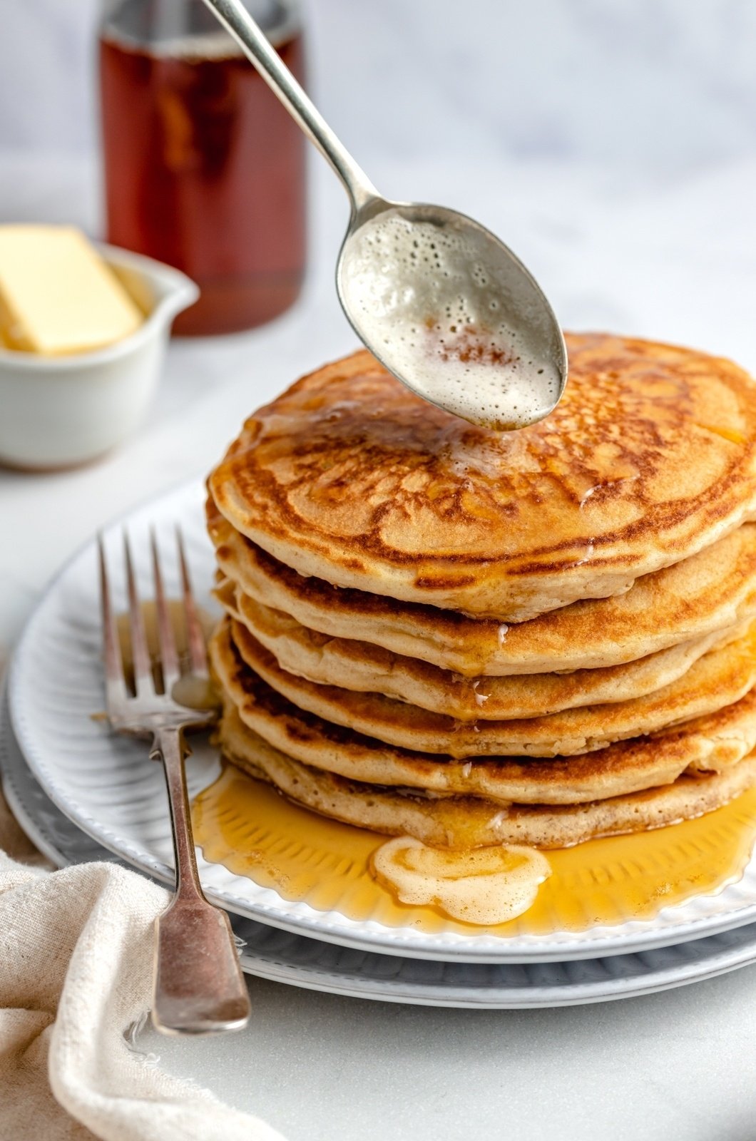 drizzling brown butter onto a stack of brown butter pancakes