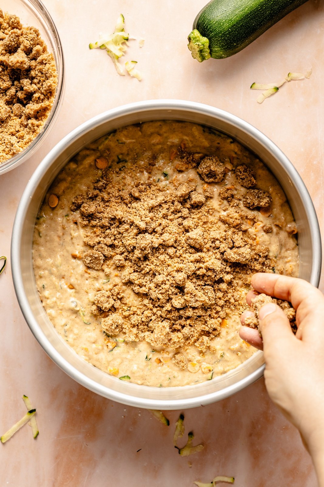 sprinkling a streusel topping over an unbaked zucchini coffee cake