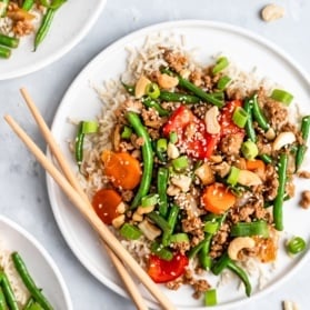 sesame chicken and green bean stir fry on a plate with chopsticks