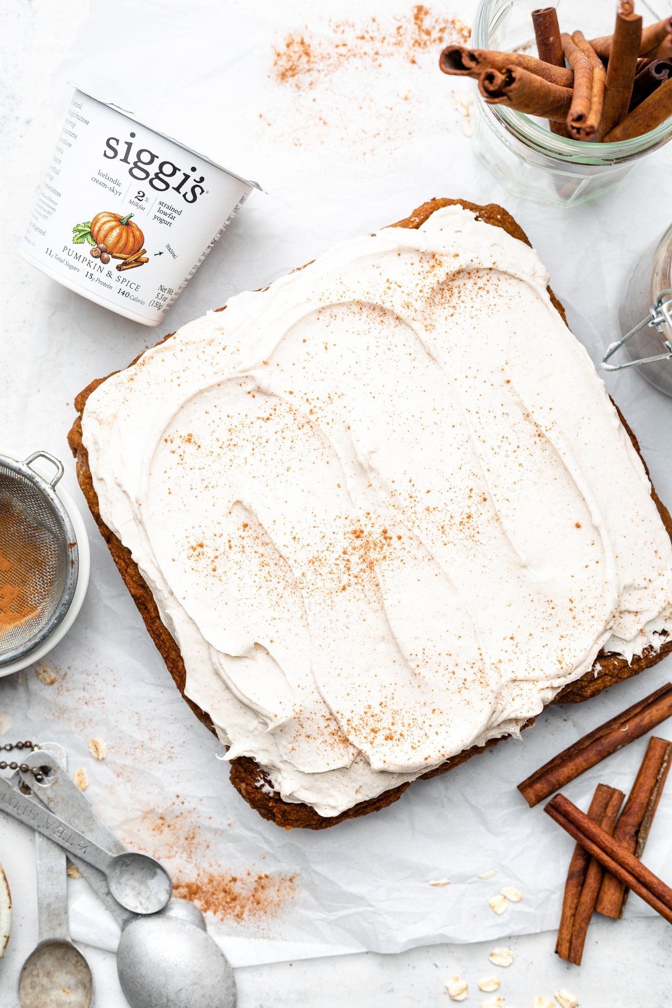 pumpkin cake with cream cheese frosting next to a container of yogurt