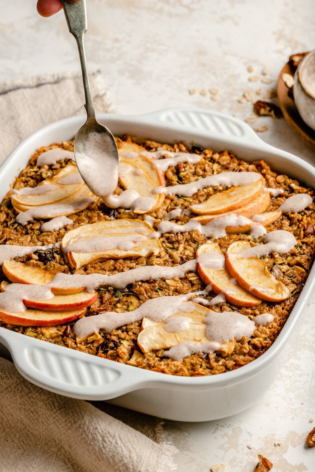 drizzling an apple zucchini oatmeal bake with a glaze