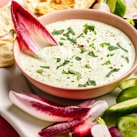 spicy green feta dip in a bowl surrounded by vegetables