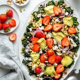 summer kale salad on a platter with strawberries and avocado