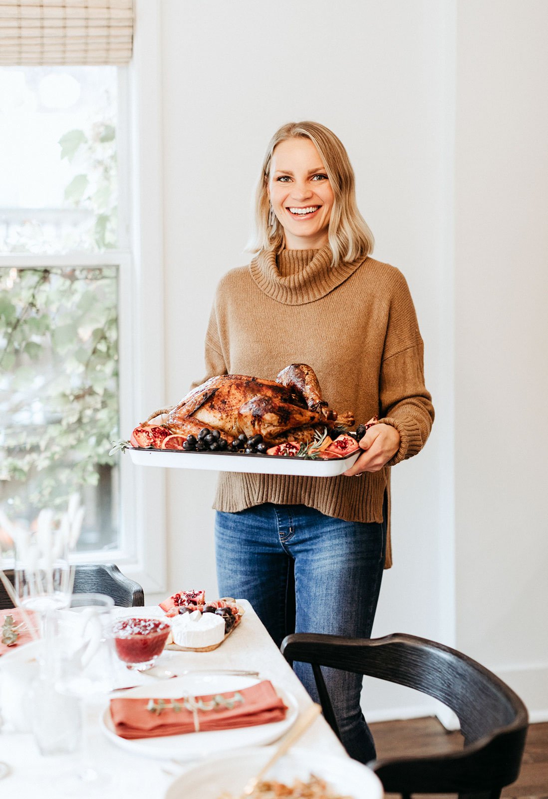 blonde woman holding a turkey on a platter