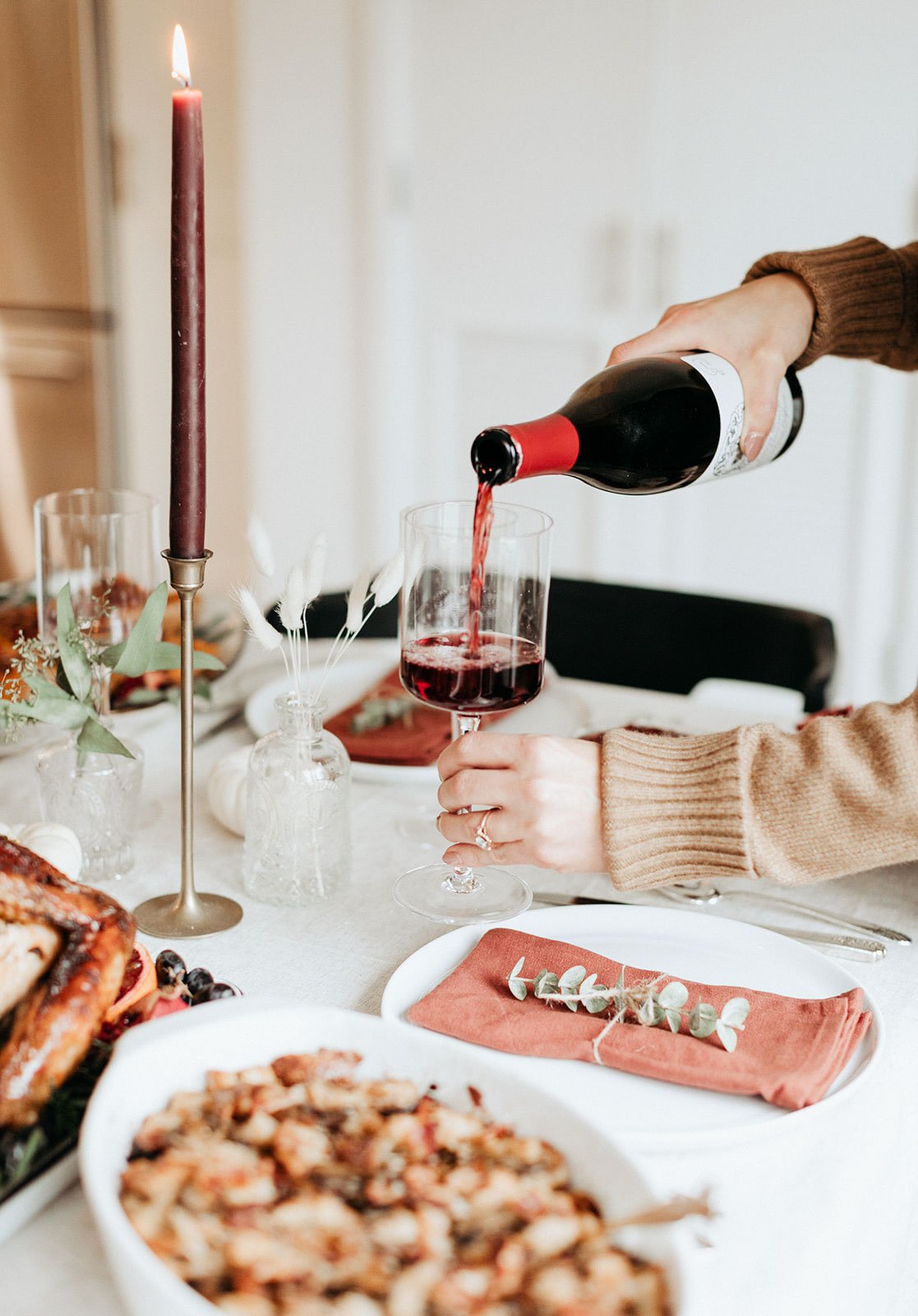 pouring wine into a glass on a thanksgiving table