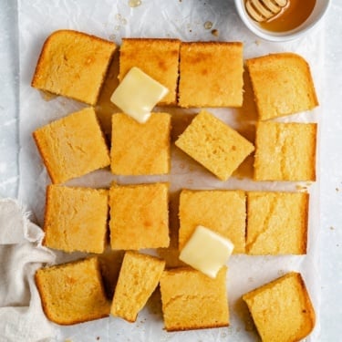 fluffy homemade cornbread cut into slices and topped with butter