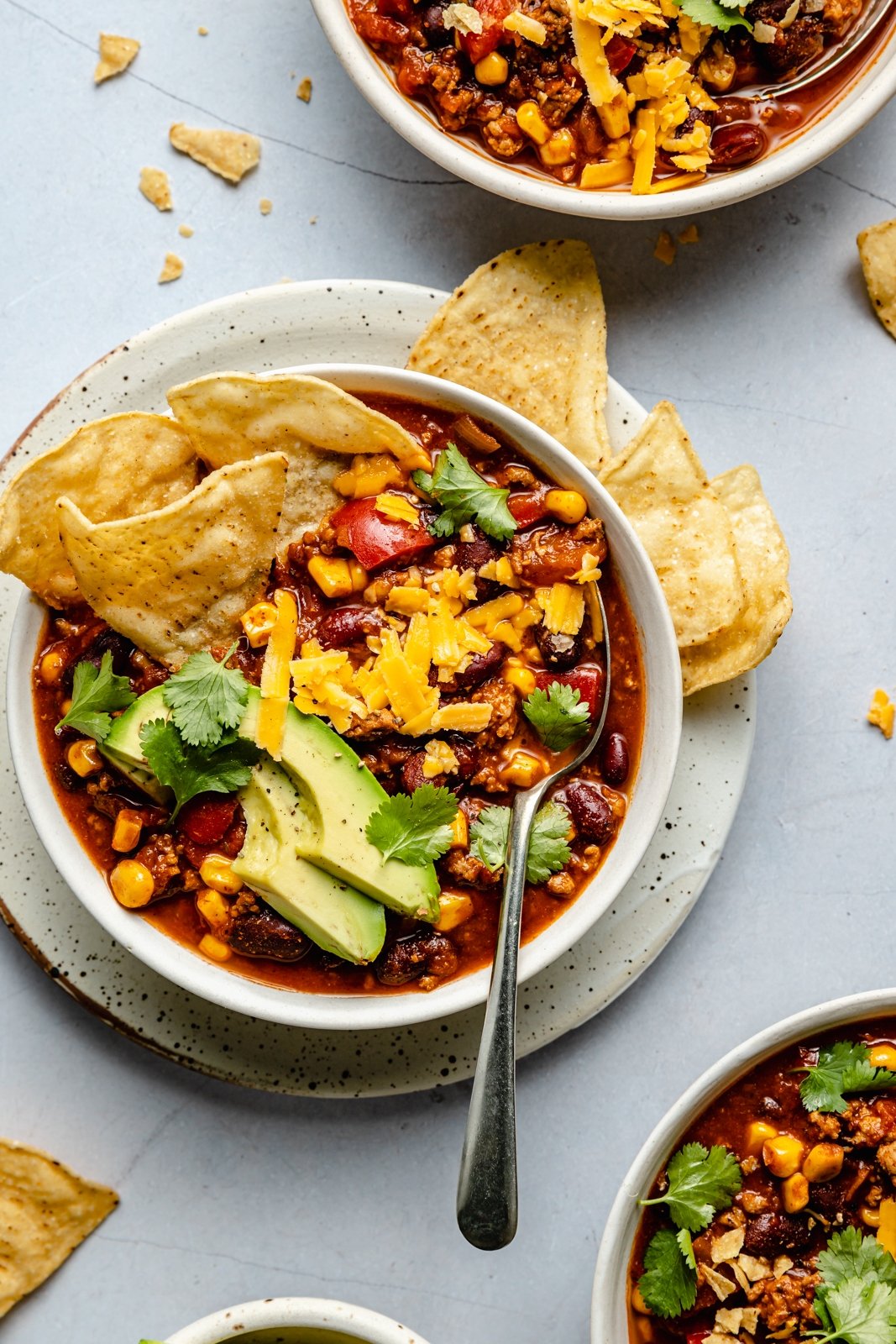 healthy turkey chili in a bowl with avocado and tortilla chips