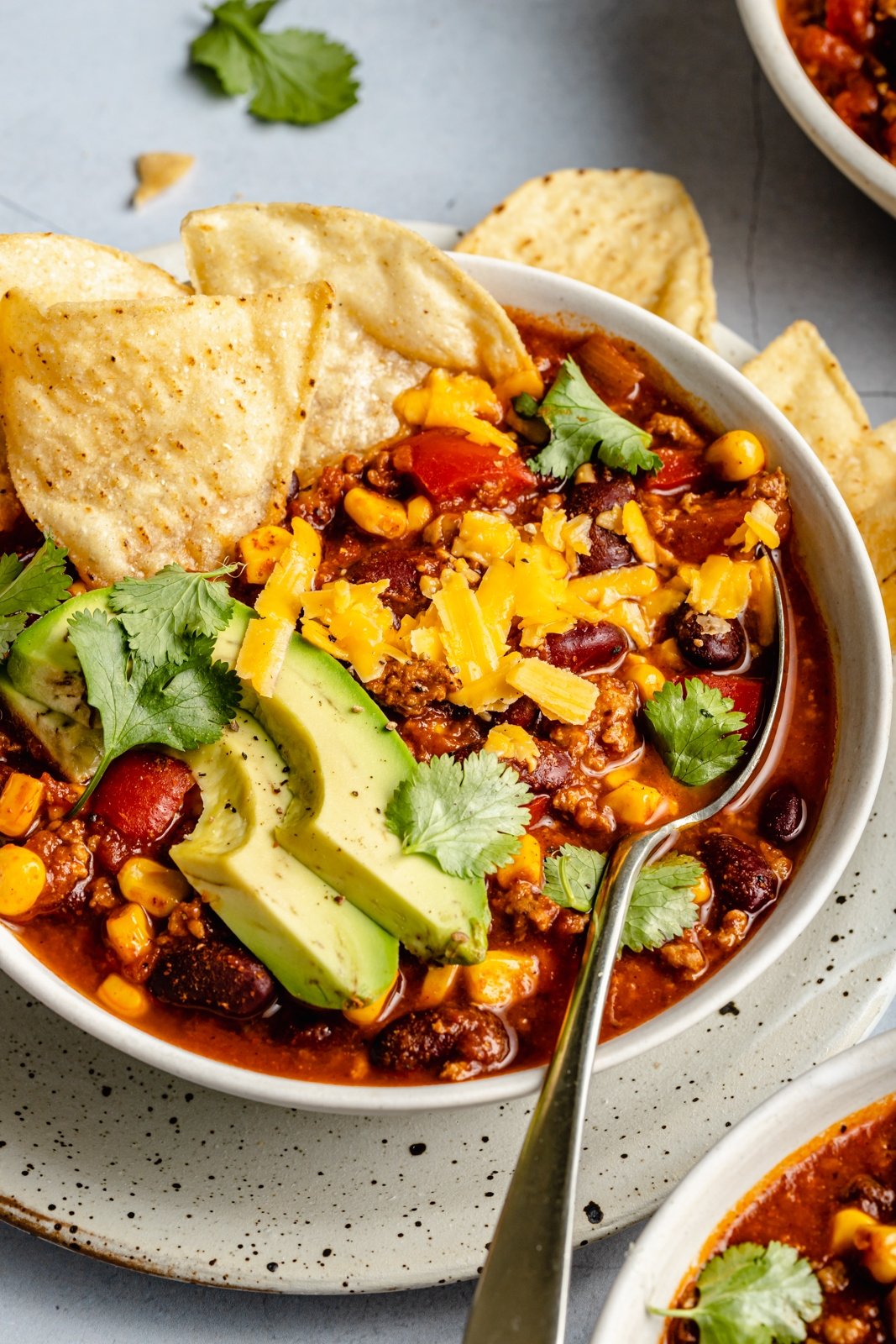 turkey chili in a bowl topped with avocado and tortilla chips